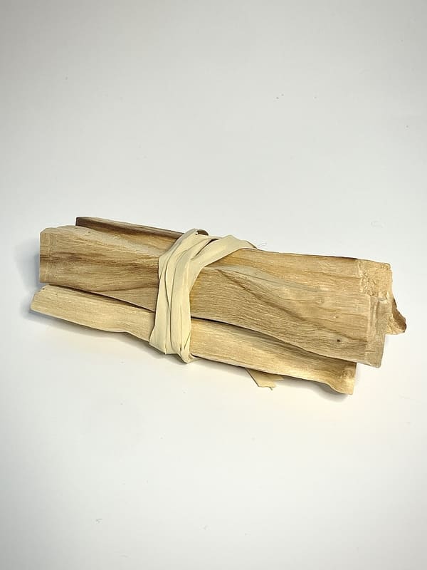 3 bâtons de Palo Santo relié ensemble par du radia sur fond banc